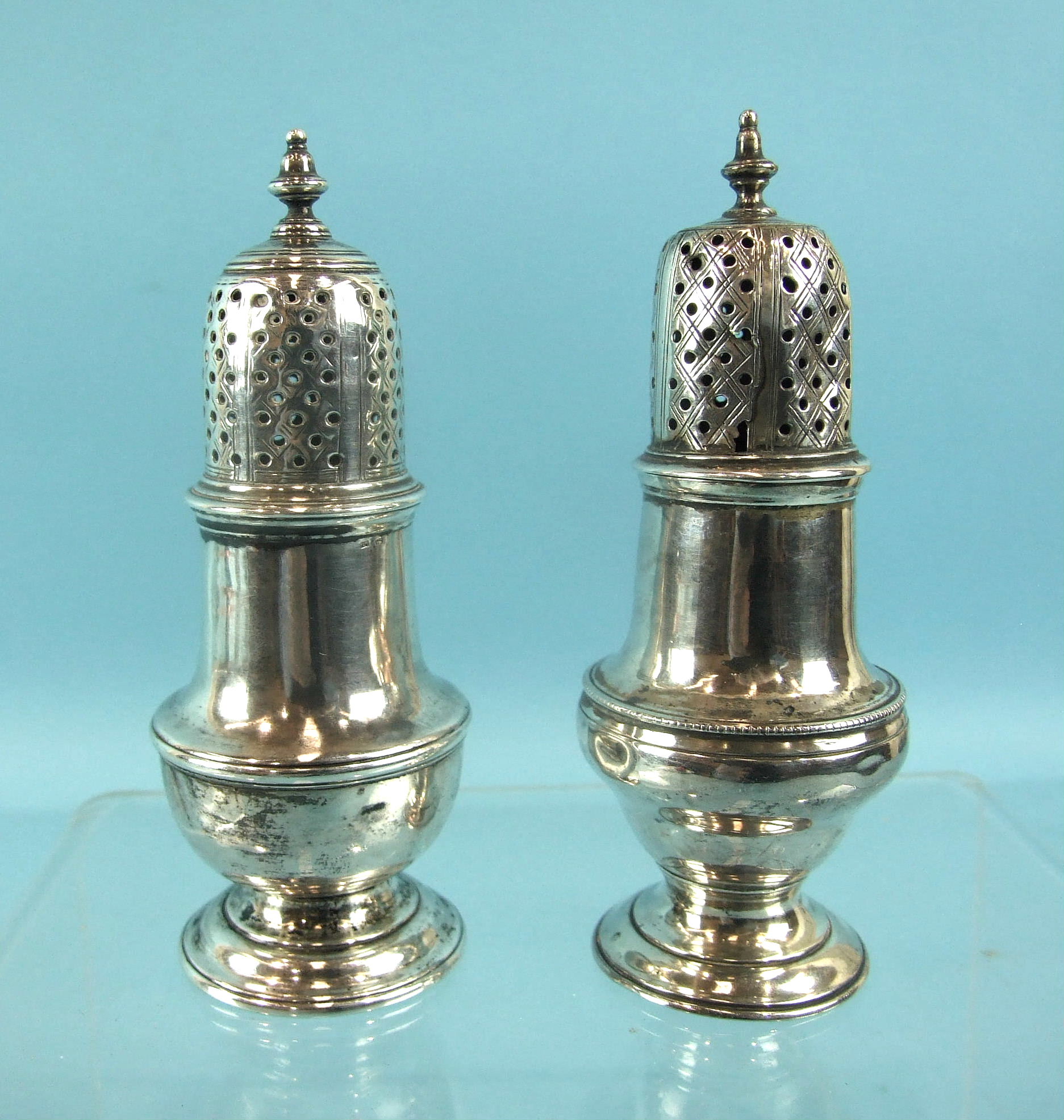 Two Georgian pepper castors of baluster form, 1747 and 1767, one with damaged lid, 12cm high, (2).