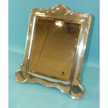 A silver-framed mirror of rectangular form, with shaped and rounded base fitted with wooden strut,