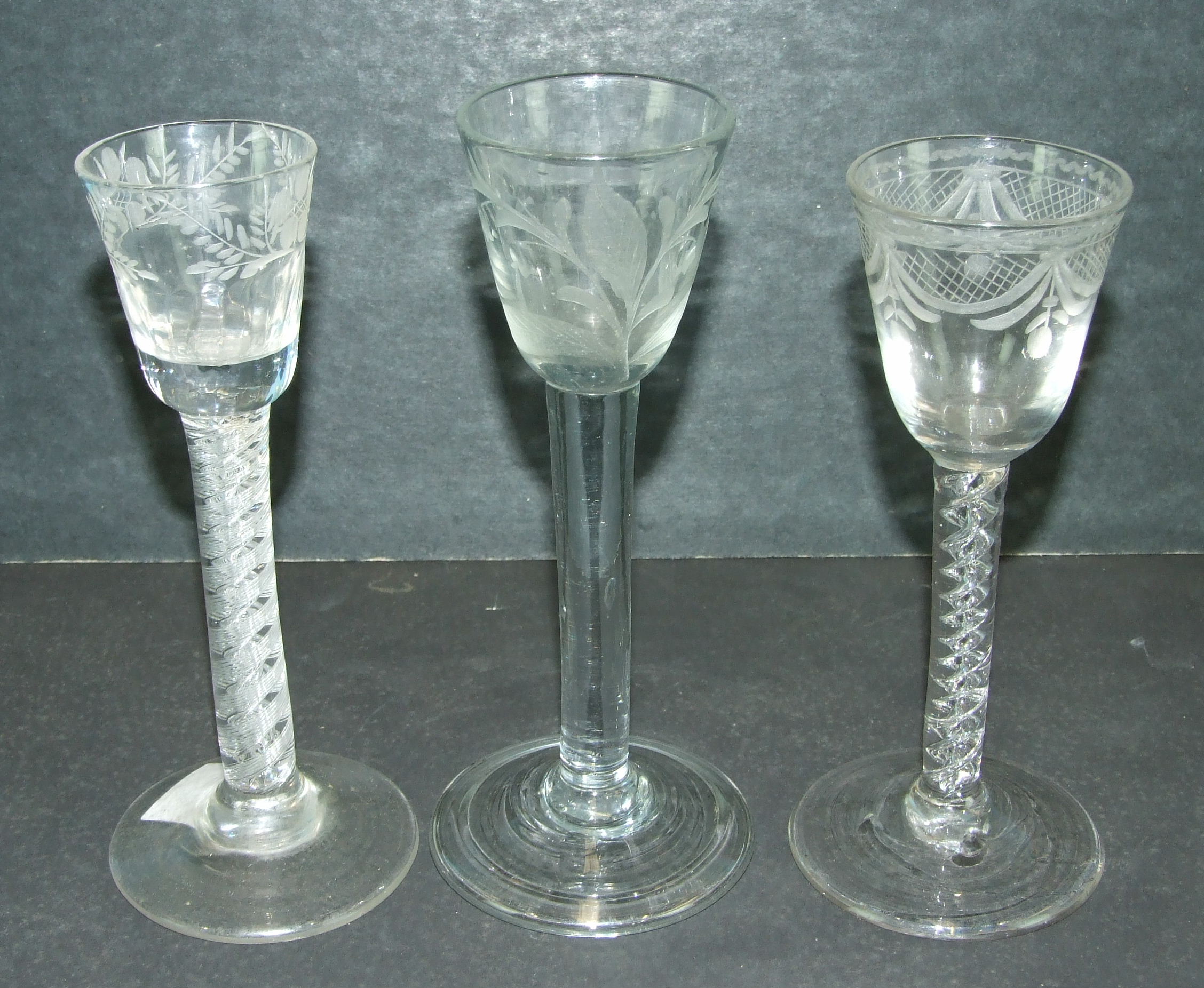 An 18th century English cordial glass with engraved floral decoration, on a plain stem, a similar