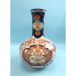 A large 19th century Japanese Imari bottle vase and cover decorated with flowers and shrubs, 32cm