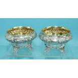 A pair of Victorian salts of compressed circular form embossed with flowers and foliage, on four