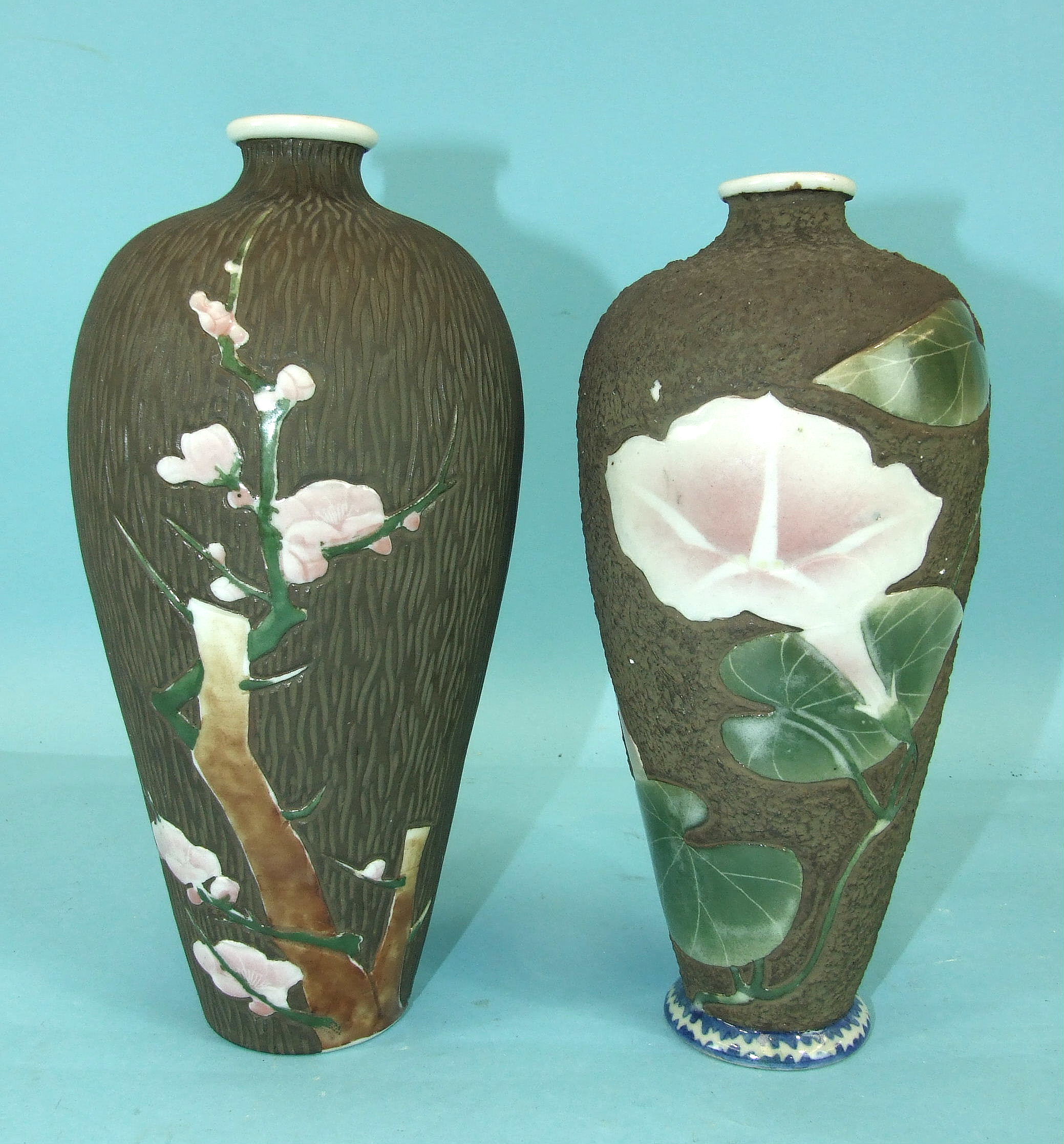 A pair of Japanese porcelain vases decorated with flowering lilies and prunus, on a wood-effect