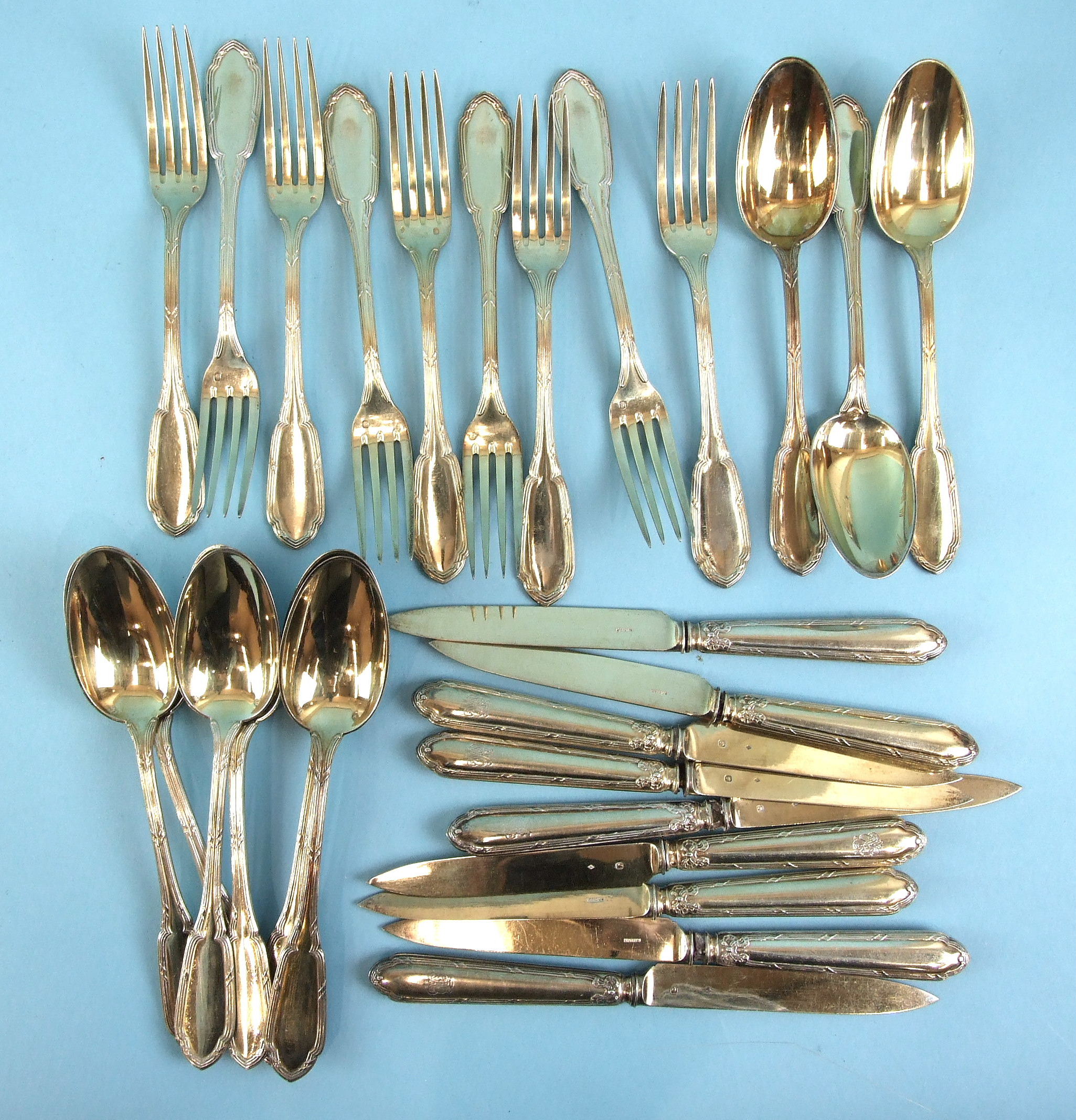 A set of nine each French silver gilt dessert spoons, table forks and knives with loaded handles,