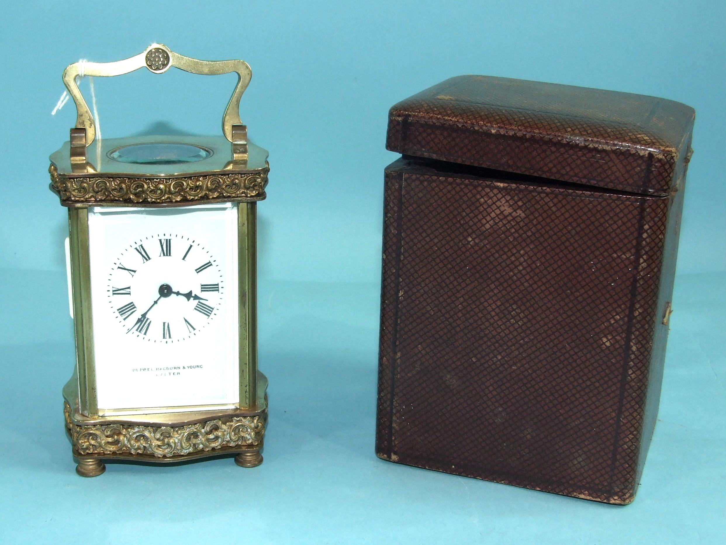 A French brass carriage timepiece, the case of serpentine outline, with decorative frieze and