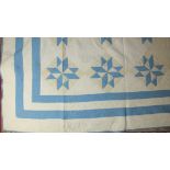 An early-20th century American patchwork quilt, with a star design hand-stitched in blue and cream