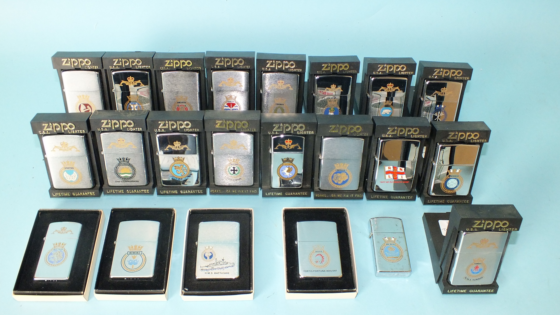 A collection of twenty-two Zippo lighters with naval crests, (all but one boxed).