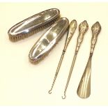 Two silver-backed clothes brushes, two silver-handled button hooks and a shoe horn, (5).