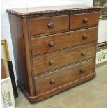A mahogany finish straight-front chest, the rectangular top with wavy edge above two small and three