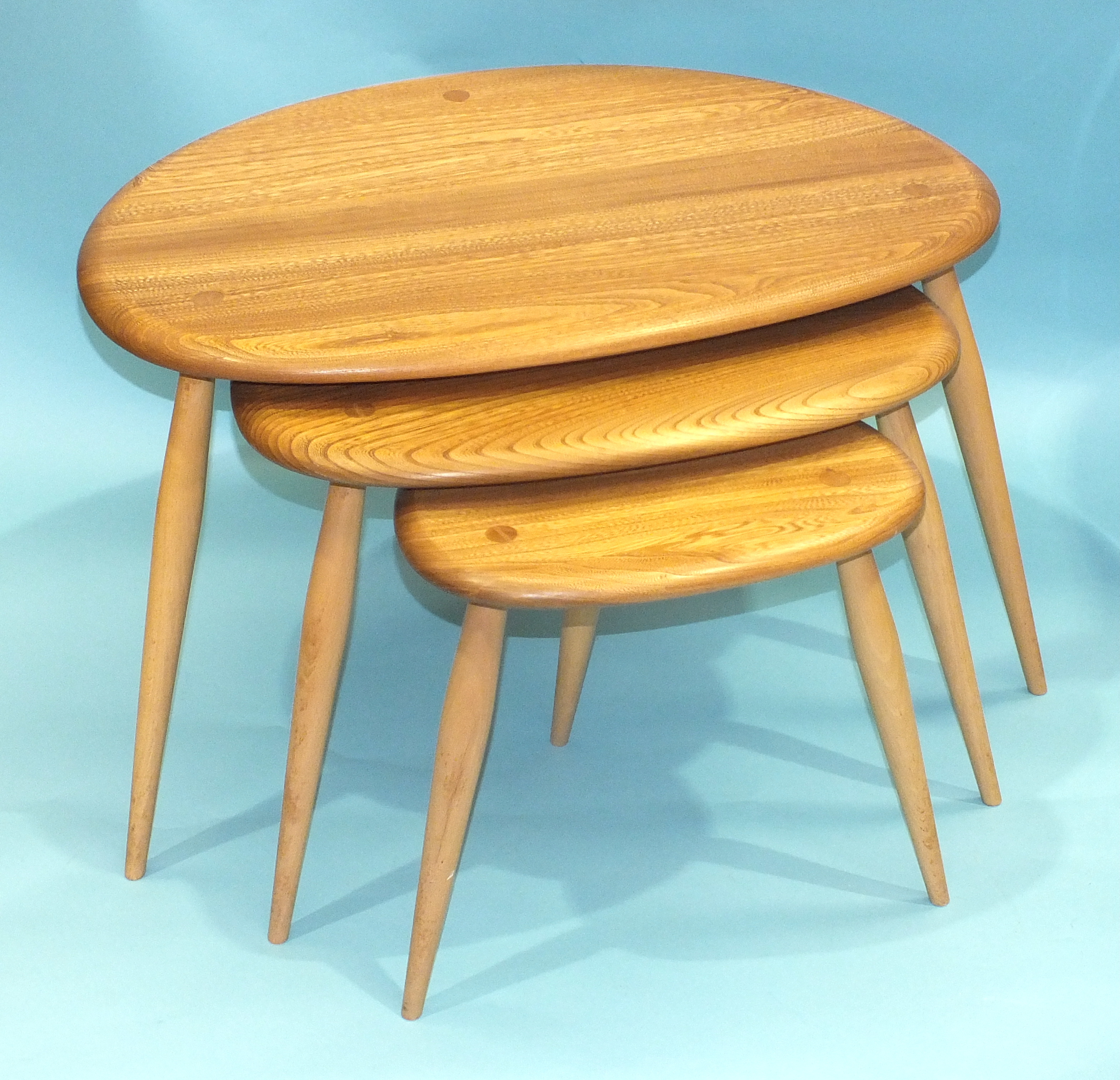 An Ercol nest of three light elm and beech 'Pebble' tables, largest 64cm wide, 41cm high.