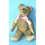 A small early-20th century teddy bear with boot button eyes, prominent snout with vertically-