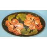 A Moorcroft Pottery oval shaped shallow bowl decorated in the 'Hibiscus' pattern with coral-coloured