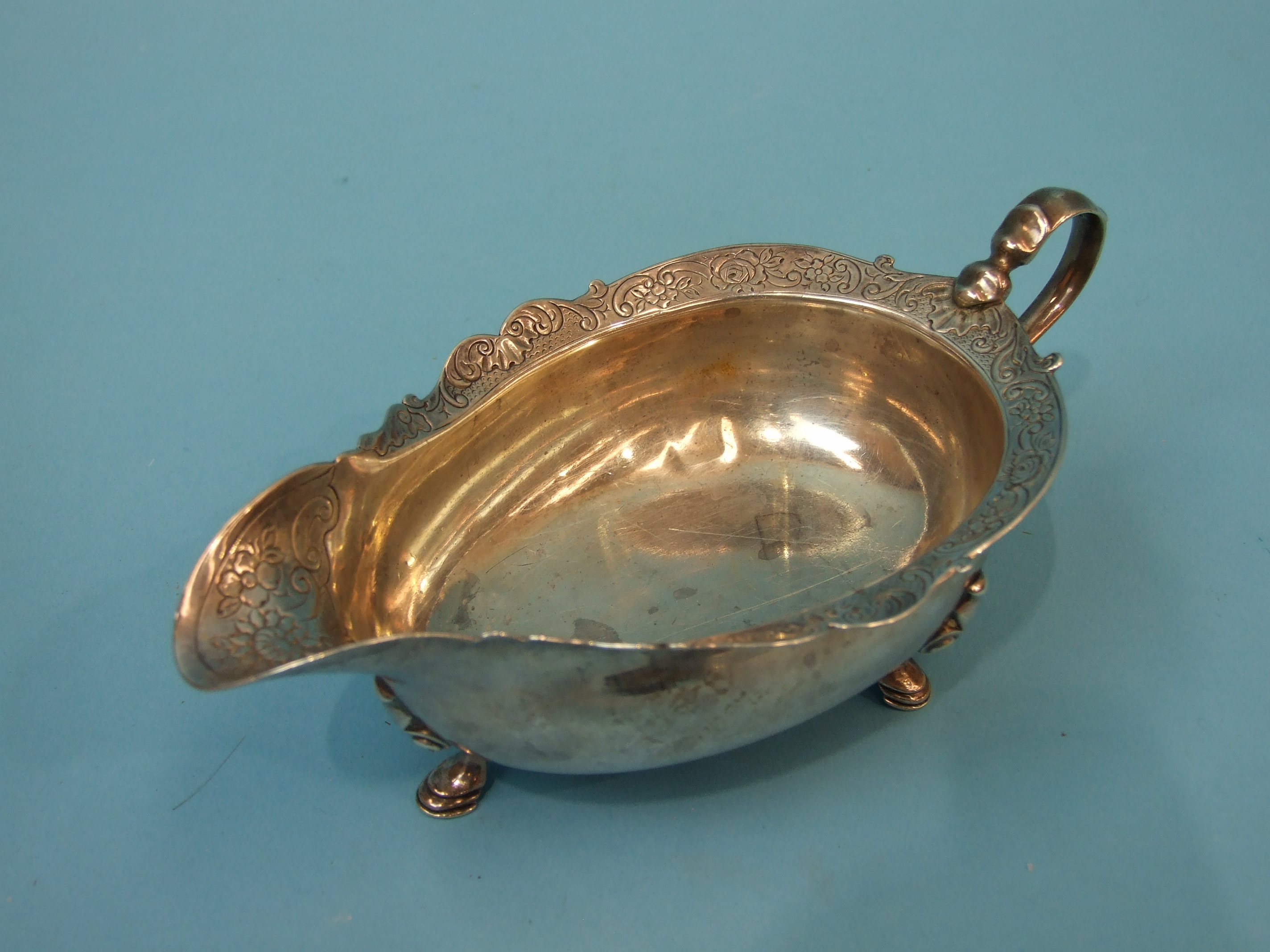 A George II Scottish cream or sauce boat on three hoof feet, with a shaped and chased rim and scroll - Image 3 of 4