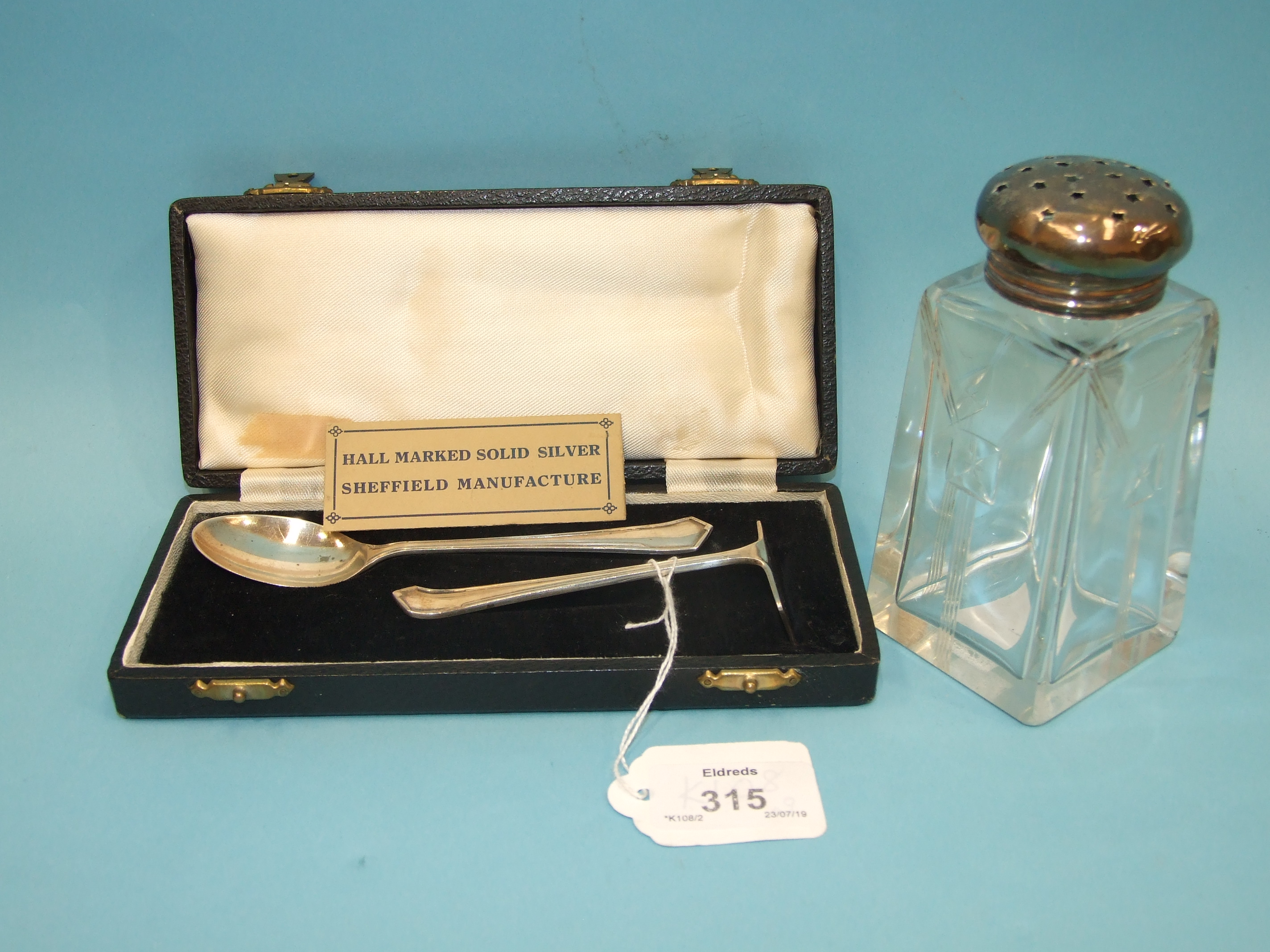 A cased silver pusher and spoon, Sheffield 1947 and a silver-topped sugar caster, marks rubbed.