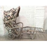 A vintage bamboo sprung lounger chair with canopy, on wheels.