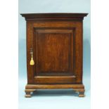 An antique oak spice or collectors cabinet, the moulded cornice above a cross-banded fielded