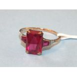 An Art-Deco-style 9ct gold ring set a synthetic ruby between two keystone-cut synthetic rubies, size