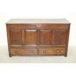 An antique oak coffer, the hinged lid above a panelled front and two base drawers, 137cm wide.