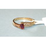 A ruby and diamond cross-over ring claw-set a marquise-cut ruby between diamond-point-set shoulders,