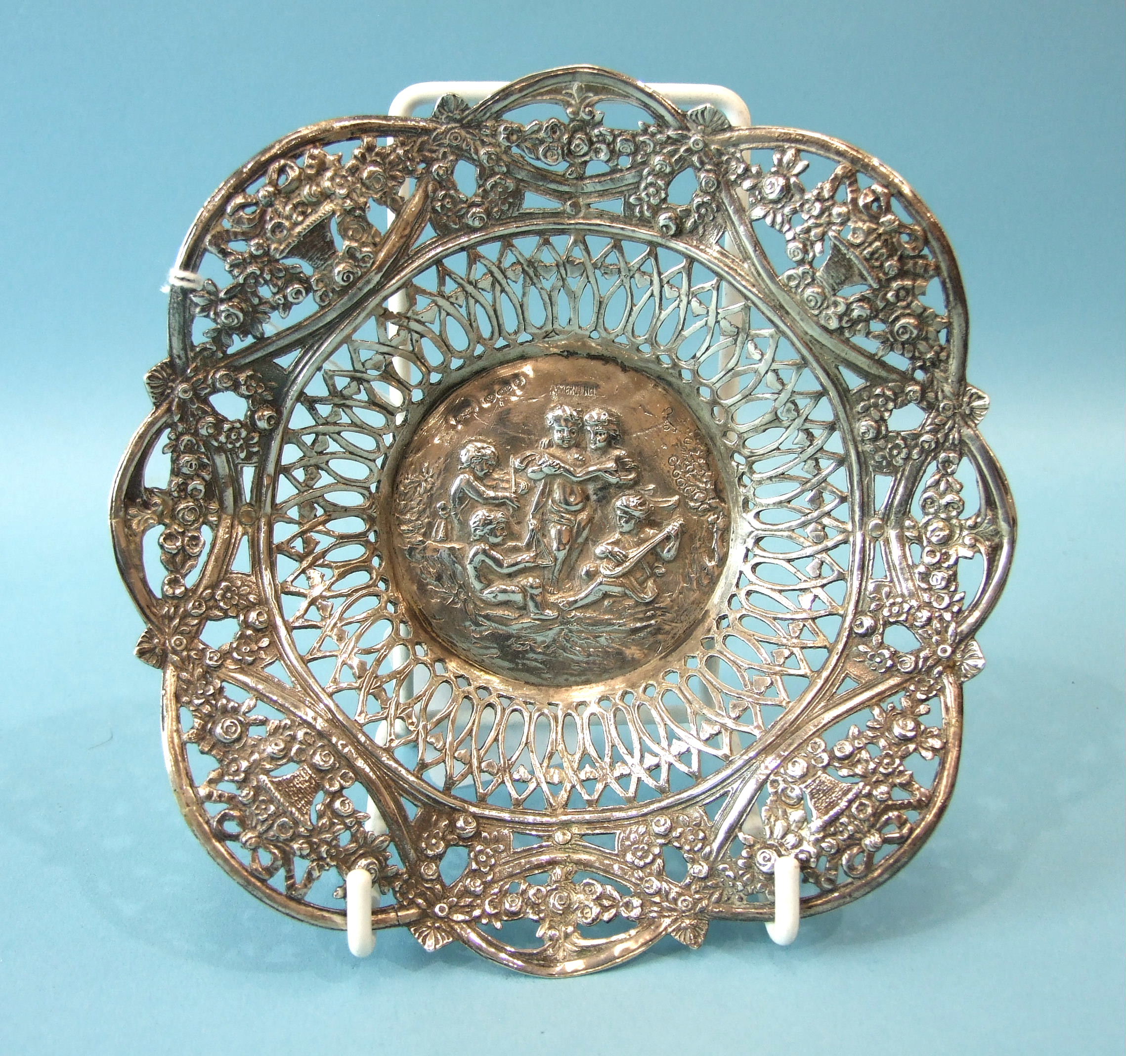 A Continental pierced circular dish, the centre embossed with putti playing musical instruments