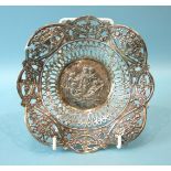 A Continental pierced circular dish, the centre embossed with putti playing musical instruments