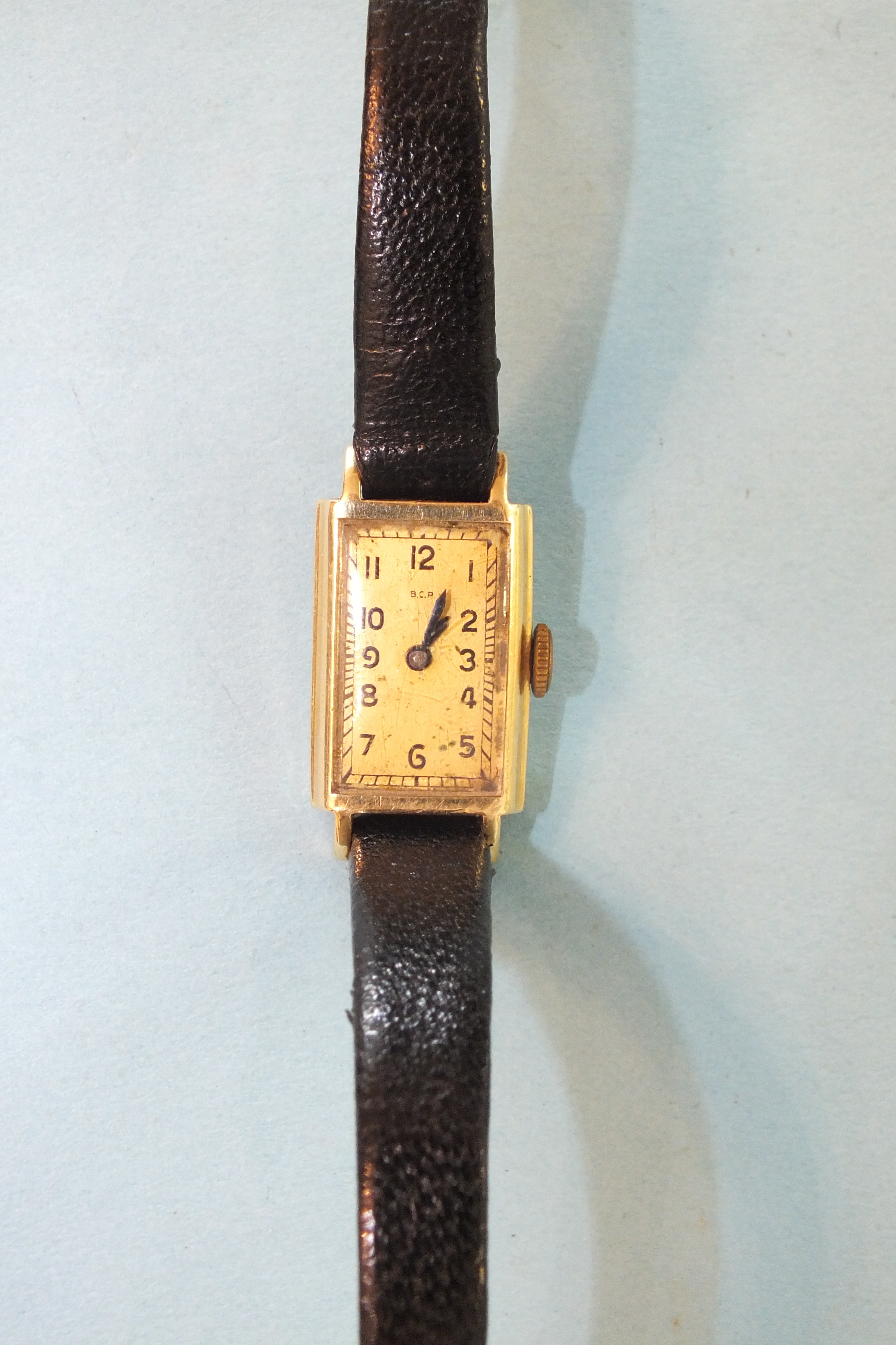 B.C.P, a lady's 14ct gold rectangular-face wrist watch, on leather strap.