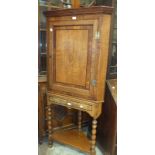 A 19th century oak corner cupboard, having a single door with central inlaid shell motif, on