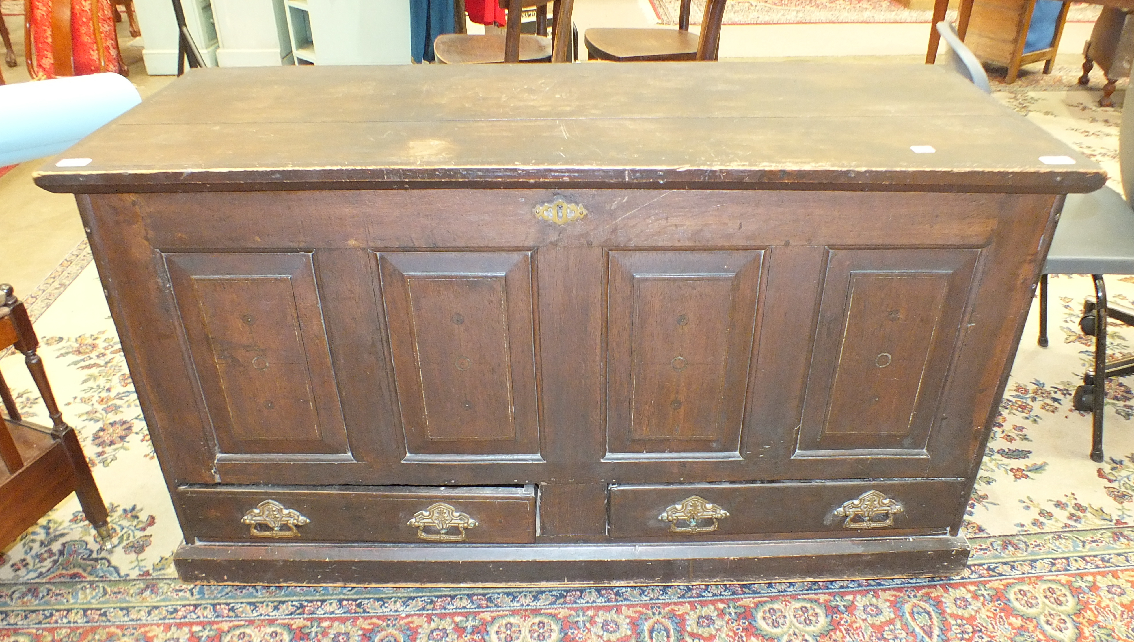 An antique oak coffer, the hinged lid above a panelled front and two base drawers, 135cm wide.