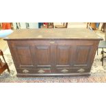 An antique oak coffer, the hinged lid above a panelled front and two base drawers, 135cm wide.