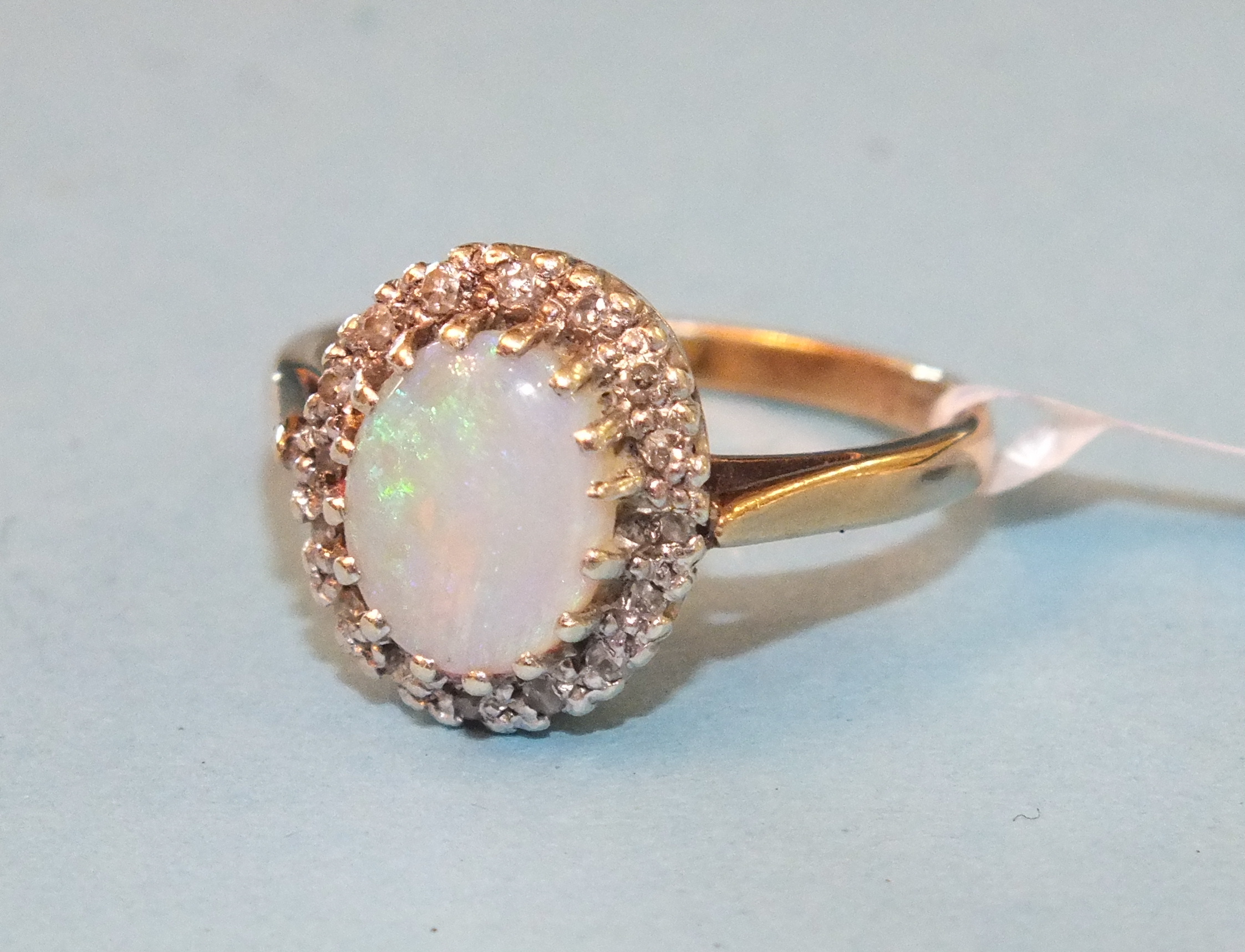 An opal and diamond cluster ring claw-set an oval opal within a border of 8/8-cut diamond points, in