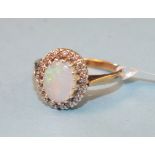 An opal and diamond cluster ring claw-set an oval opal within a border of 8/8-cut diamond points, in