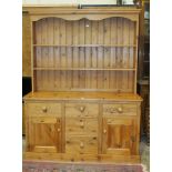 A modern pine dresser, the open shelved top above a base fitted with an arrangement of five