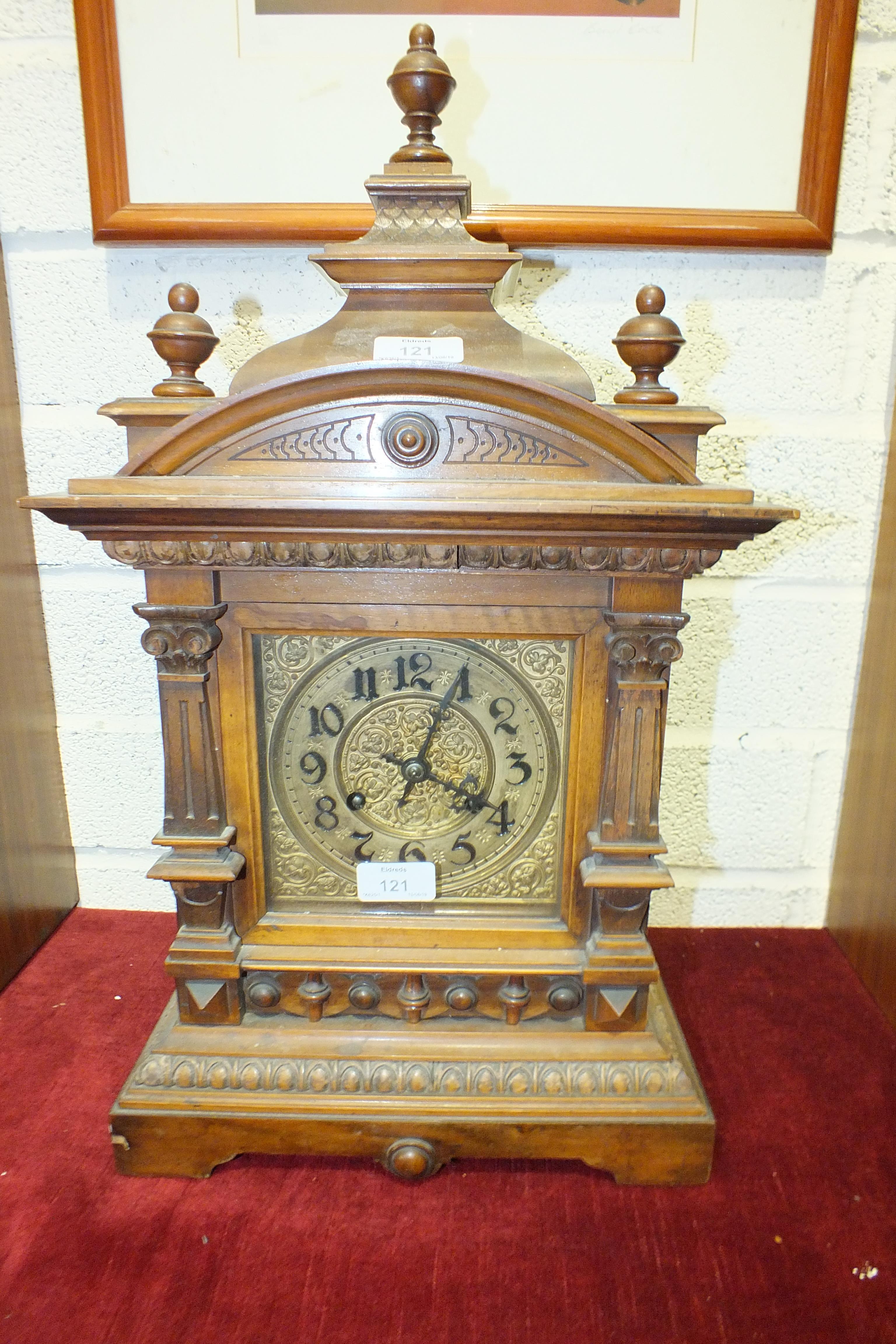 A walnut-cased mantel clock of architectural form with brass dial, the movement striking on a
