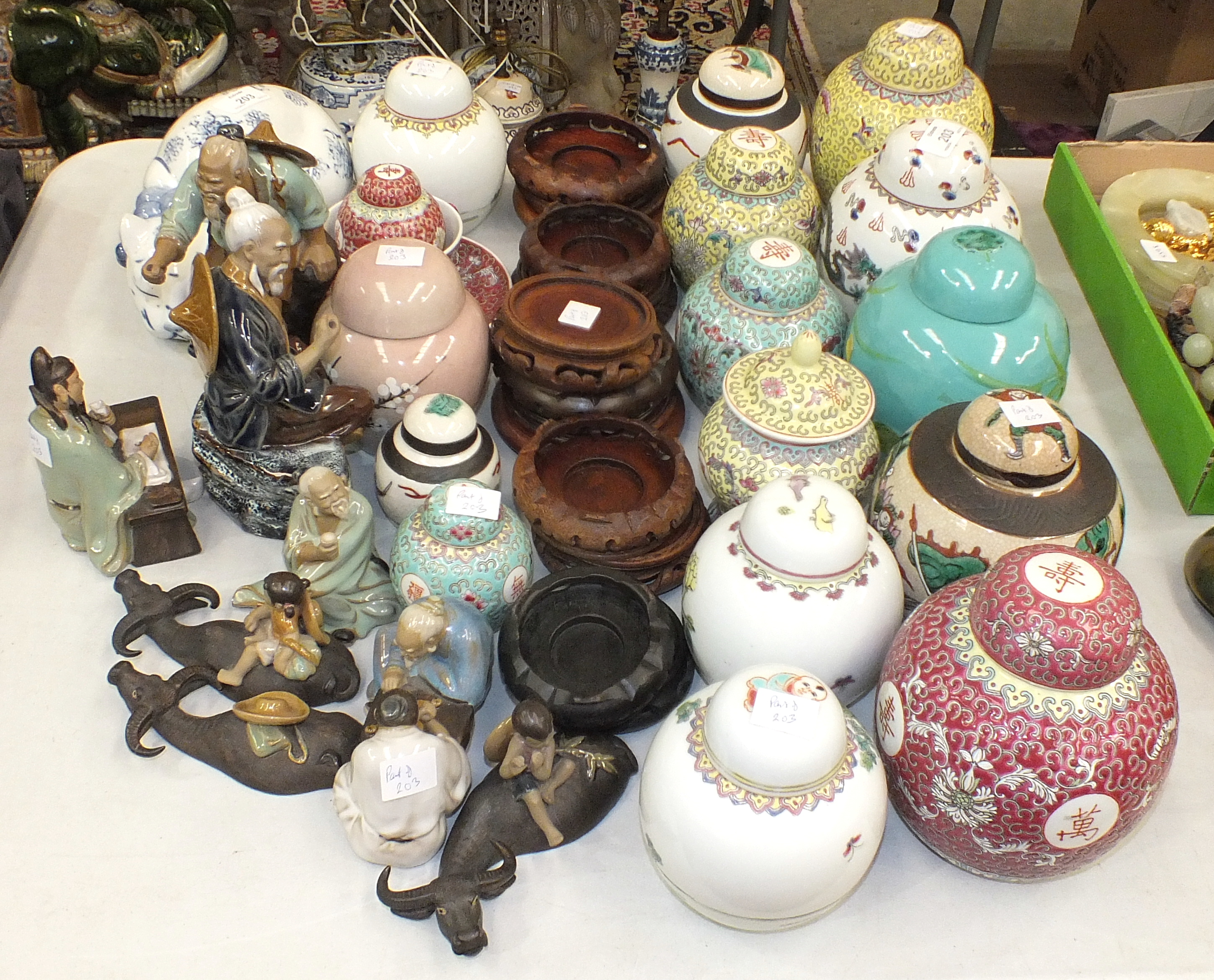 A collection of various modern coloured ceramic ginger jars and covers, with wooden stands, modern