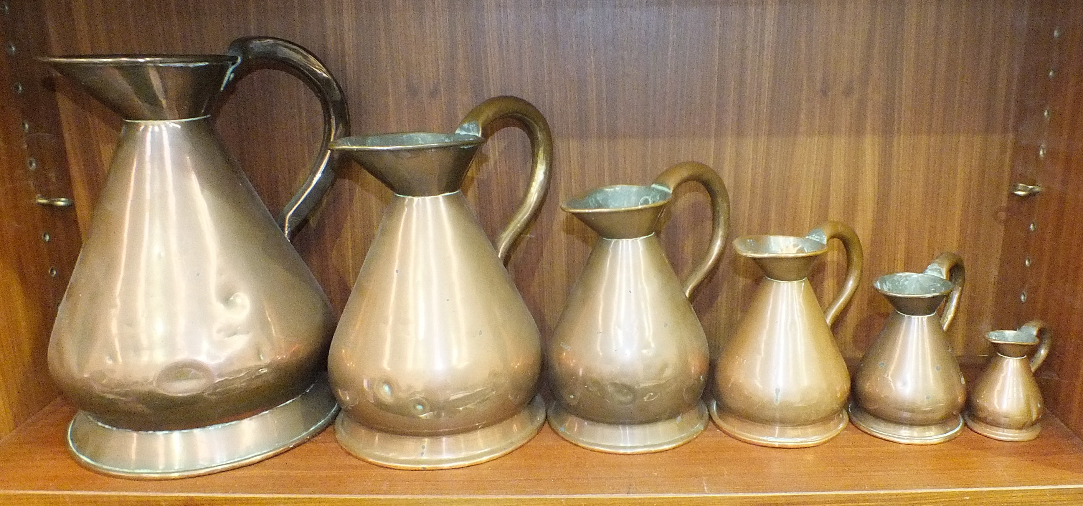 A harlequin set of six graduated copper measures, 1 gallon - ½ gill, the pint measure stamped Burt