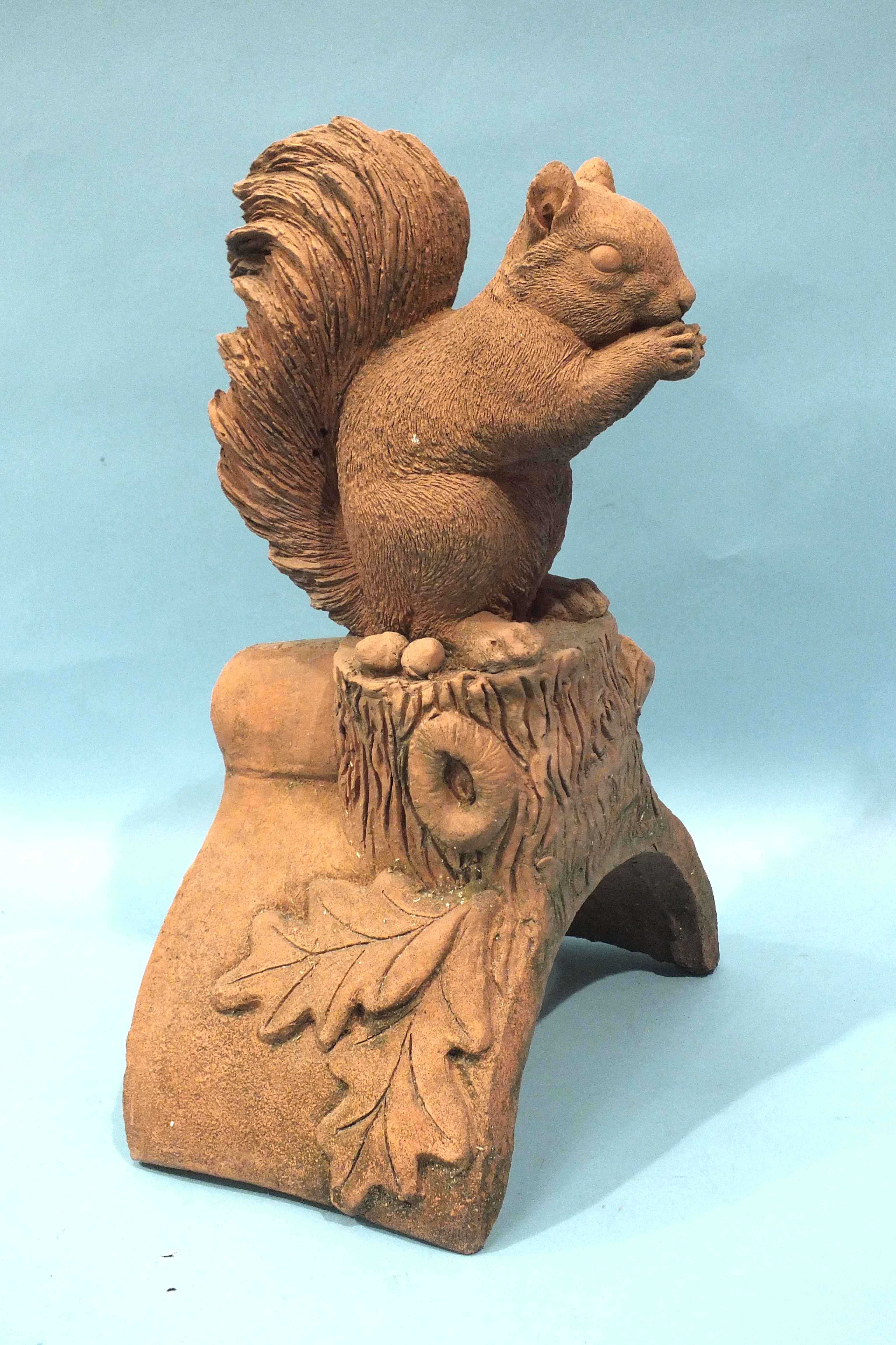 A modern terracotta roof tile ridge finial depicting a squirrel, 17cm wide 40cm high.