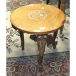 An Indian hardwood circular-top table with inlaid decoration, on three elephant mask supports,