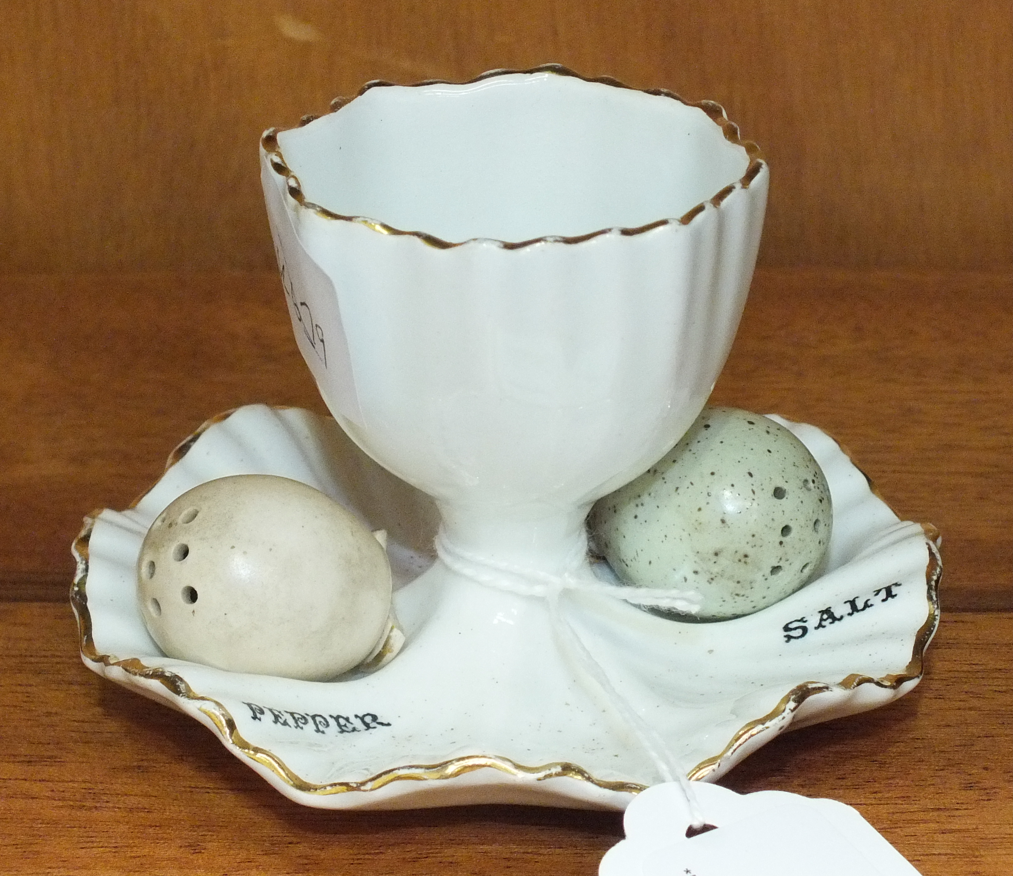 A Carltonware egg cup, 6cm high, with a salt and pepper in the form of two bird's eggs.