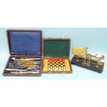 A cased set of drawing instruments, a small set of scales and weights and a travelling chess set, (