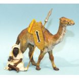 A painted spelter figure group of an Arab seated and holding a pipe, (pipe lacking), with a camel,