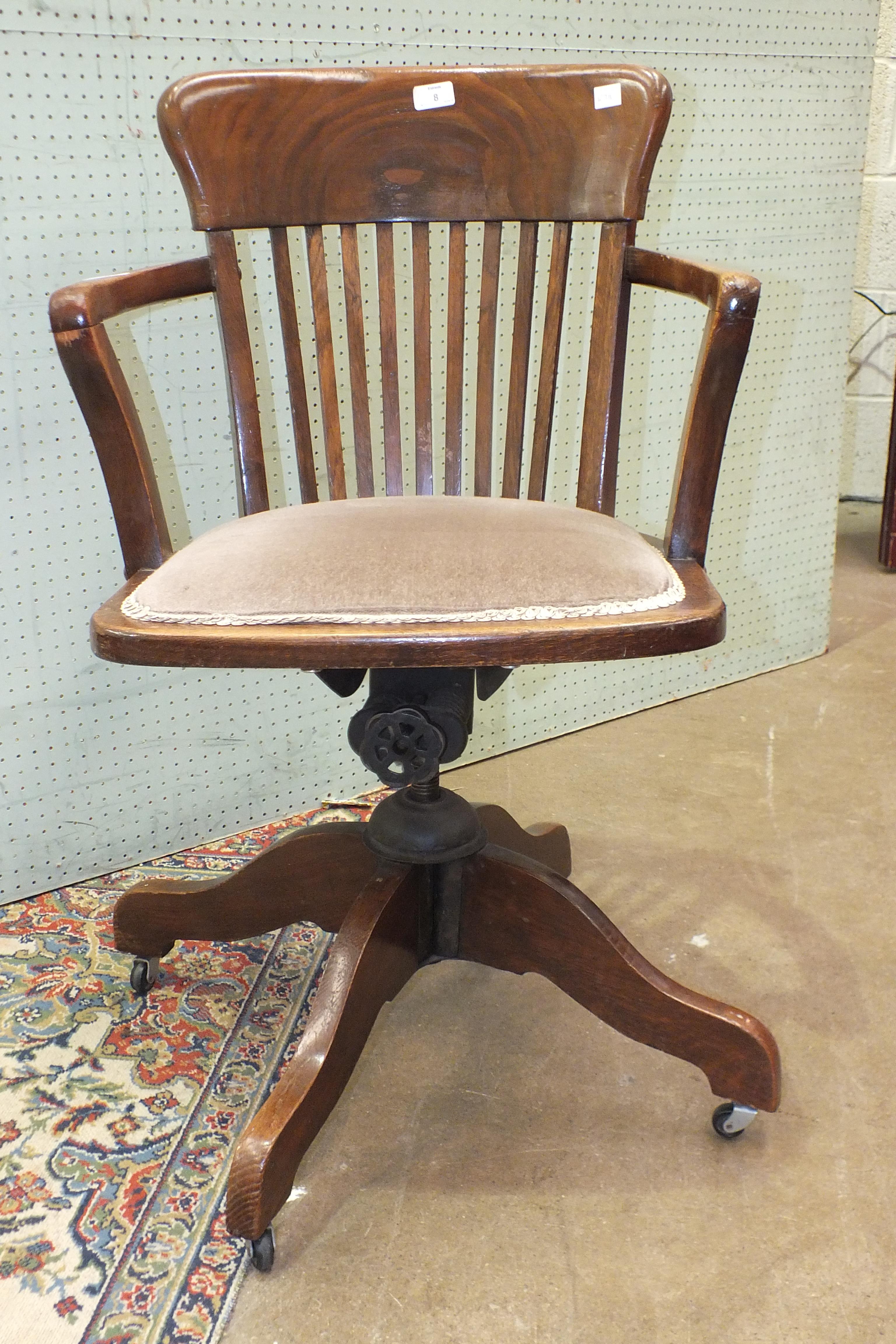 An oak swivel chair with padded seat, on quadruped support.