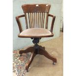 An oak swivel chair with padded seat, on quadruped support.