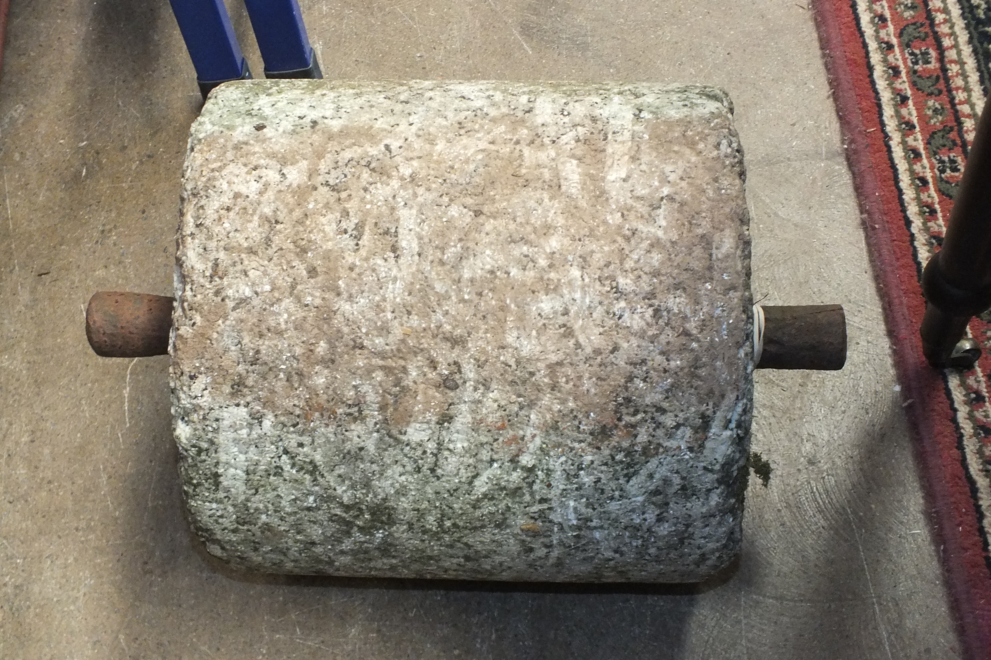 A small granite roller with iron lugs, 29cm long.