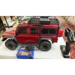 A Traxxas battery-powered remote-control Land Rover Defender with plastic body, two charger packs