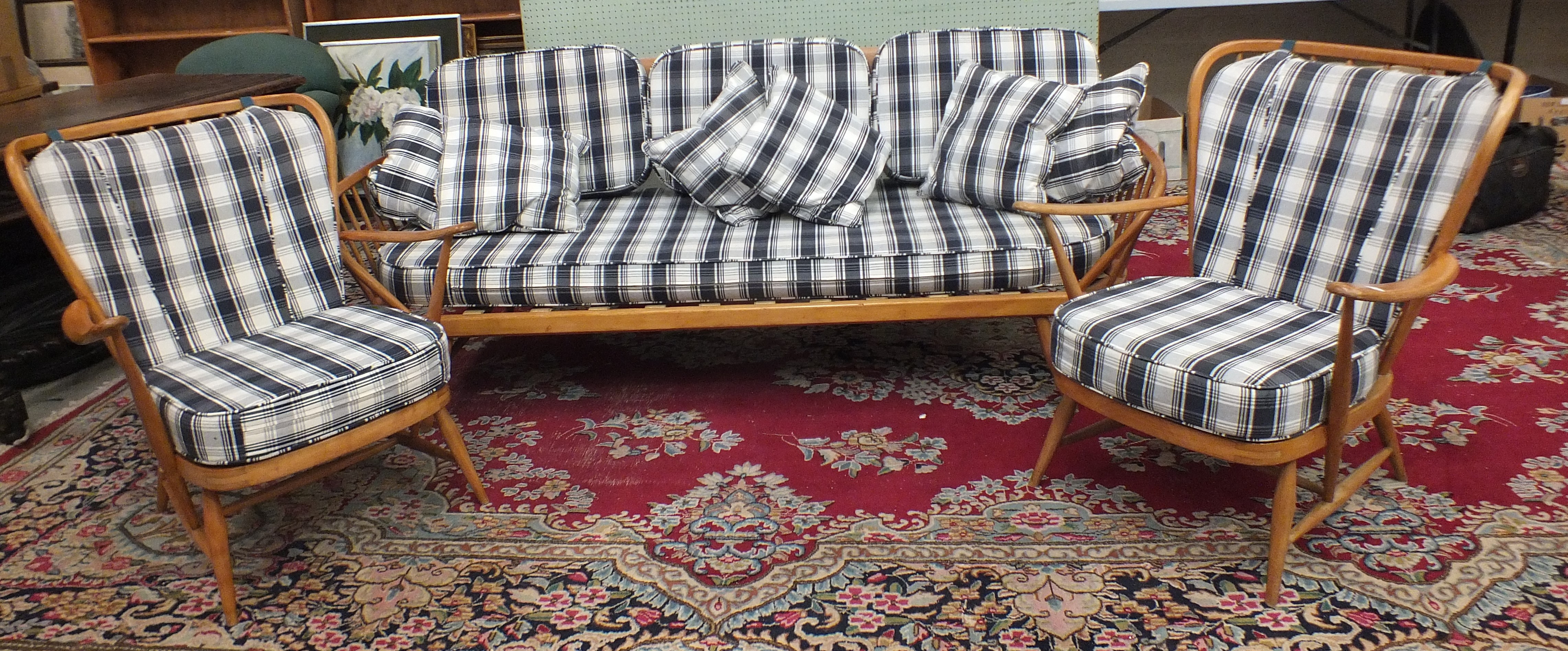 An Ercol cottage suite, comprising a three-seater settee and two armchairs, with spindle backs and