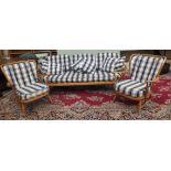 An Ercol cottage suite, comprising a three-seater settee and two armchairs, with spindle backs and