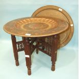 A brass circular Benares tray with peacock and leaf decoration, 61cm diameter, with folding carved