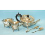 A George V silver three-piece tea service of plain form, with wavy rim, on shaped legs with hoof
