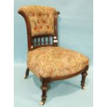 A Victorian low nursing chair, the flared button back and upholstered seat on short turned fluted