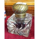 A heavy moulded glass inkwell with brass lid, a brass figure of a gecko with ruby-coloured eyes
