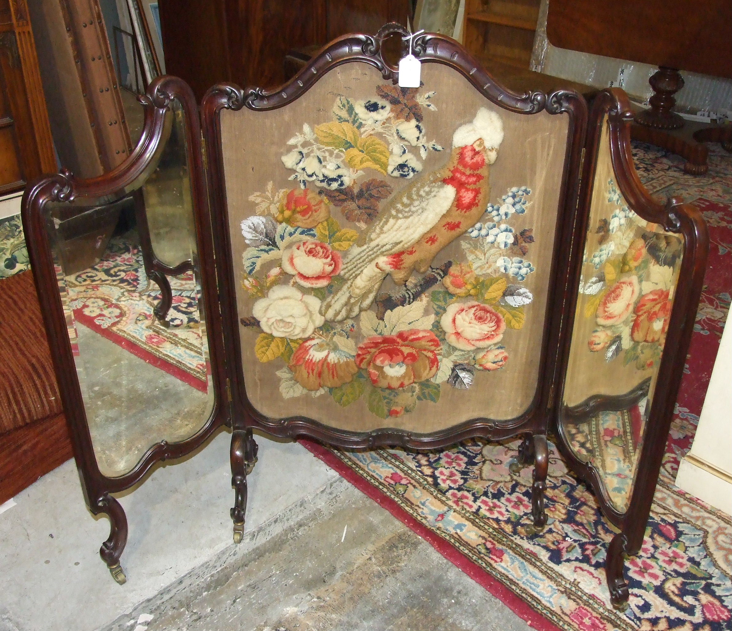 An early-20th century triptych fire screen, the central panel decorated with a needlework and bead